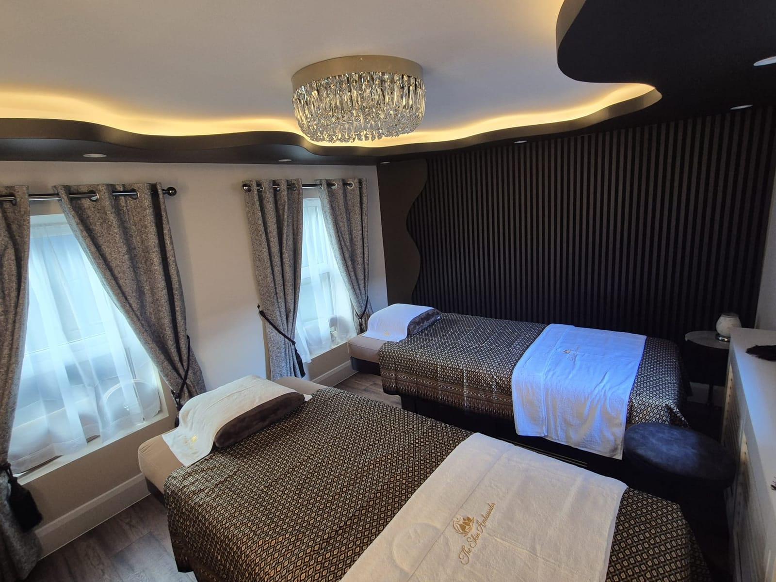 Two massage beds dressed in black and gold Thai silk beneath a crystal chandelier and softly lit curved ceiling