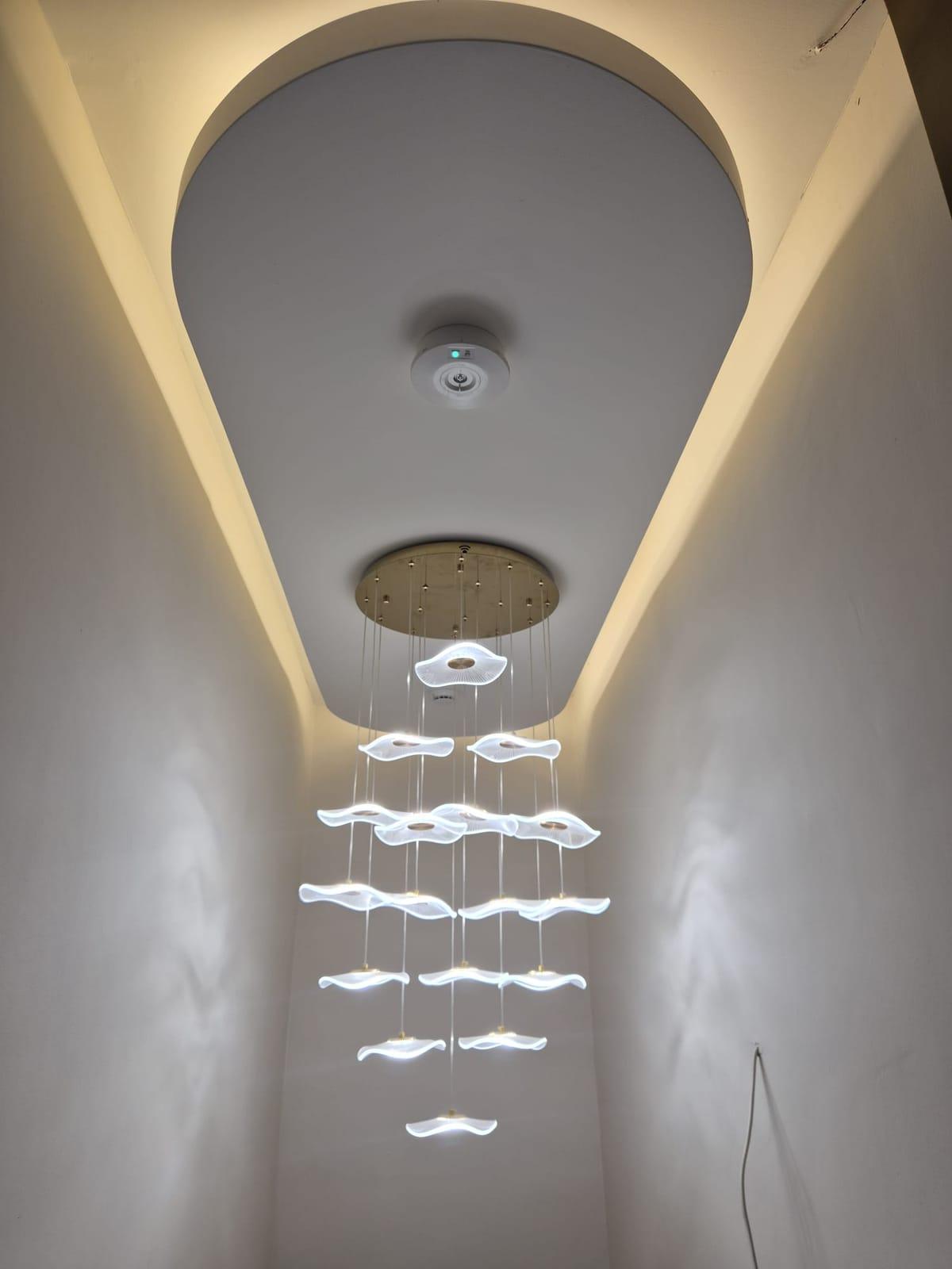 A cascading pendant light of glowing lotus-leaf shapes beneath a softly lit oval ceiling